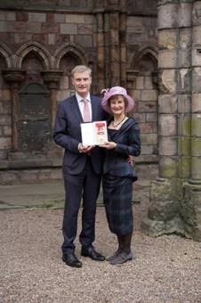 Two people holding a plaque in front of a building

Description automatically generated with medium confidence